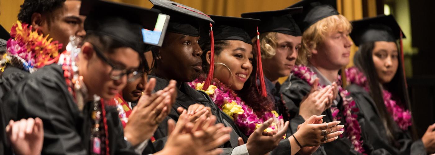 seated students applauding at graduation