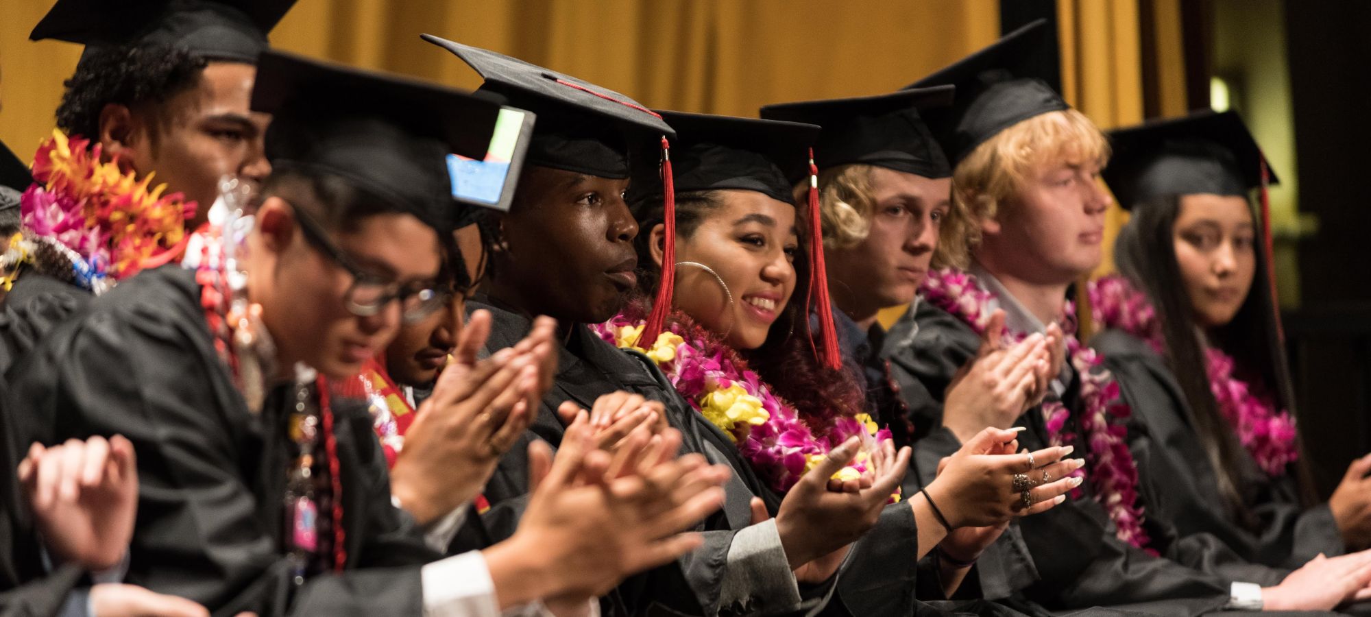 seated students applauding at graduation